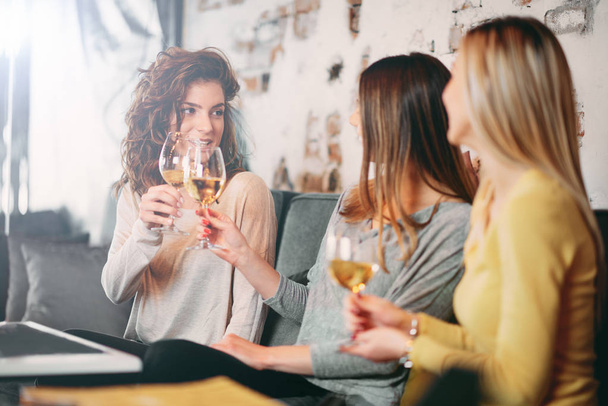 Vriendinnen wijn drinken en chatten tijdens de vergadering in de bar. - Foto, afbeelding