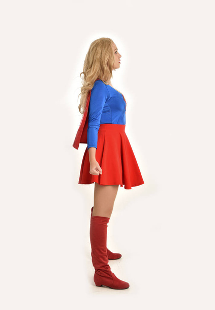 スーパー ヒーローの衣装、立ちポーズ、白いスタジオ背景に分離を着てきれいな女の子の完全な長さの肖像画. - 写真・画像