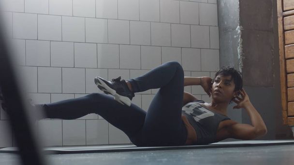 Seitenansicht der schwarzen Frau macht einen Bauch Routine auf dem Boden i synny Loft - Foto, Bild