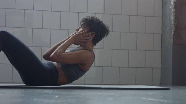 vista lateral de la mujer negra hace una rutina abdominales en el piso sinny loft
 - Foto, imagen
