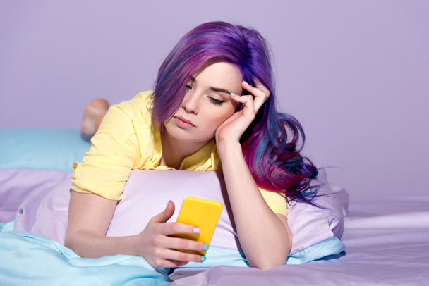 βαρεθεί νεαρή γυναίκα χρησιμοποιώντας το smartphone στο κρεβάτι - Φωτογραφία, εικόνα