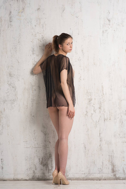 young beautiful girl posing nude in studio, standing in black blouse near white wall - Fotografie, Obrázek