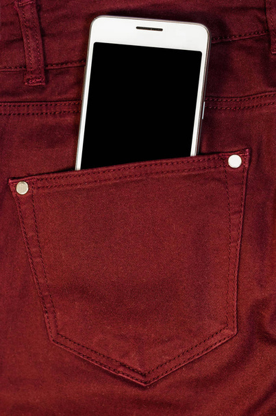 Nahaufnahme Bussines Mode stilvolle Smartphone-Bildschirm kopieren Raum weißes Handy in roten Jerry Jeans Gesäßtasche Jeans Hipster  - Foto, Bild