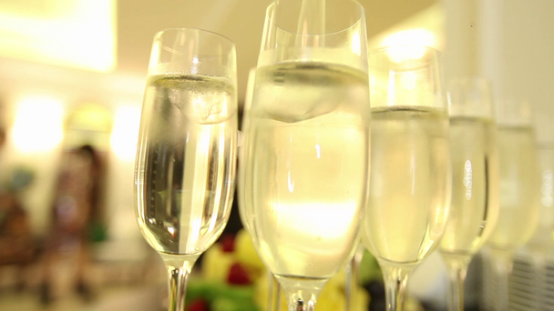 Sprankelende champagne wijn in glazen in de voorkant van de warme open haard. Close-up - Video
