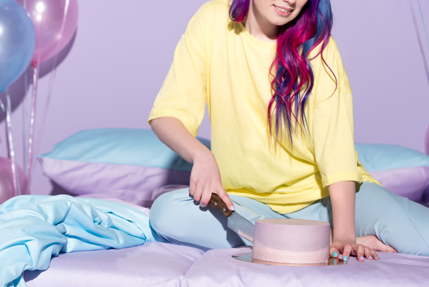 ritagliato colpo di sorridente giovane donna taglio torta di compleanno a letto
 - Foto, immagini