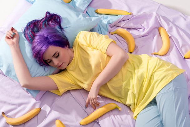 high angle view of young woman lying in bed with bananas - Фото, зображення