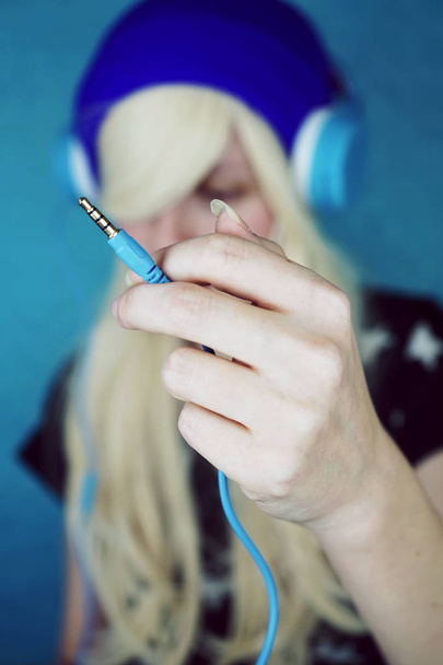 Retrato de mujer rubia joven en azul auriculares escuchando música de fondo - Foto, Imagen