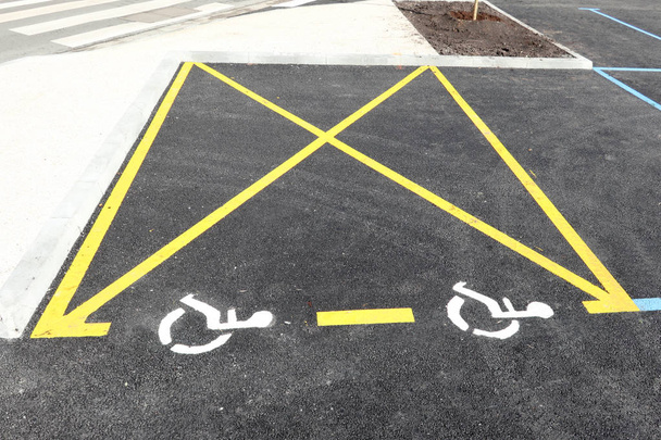 Κίτρινο αναπήρων απενεργοποιημένο εικονίδιο σημείου στο χώρο στάθμευσης σε υπαίθριο χώρο στάθμευσης αυτοκινήτων - Φωτογραφία, εικόνα