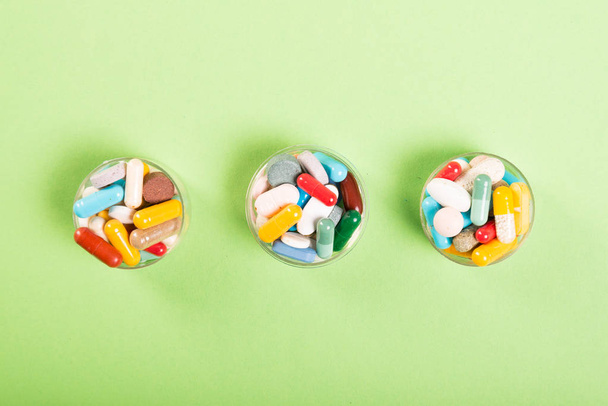 Drie kopjes kleurrijke pillen en tablet - Foto, afbeelding