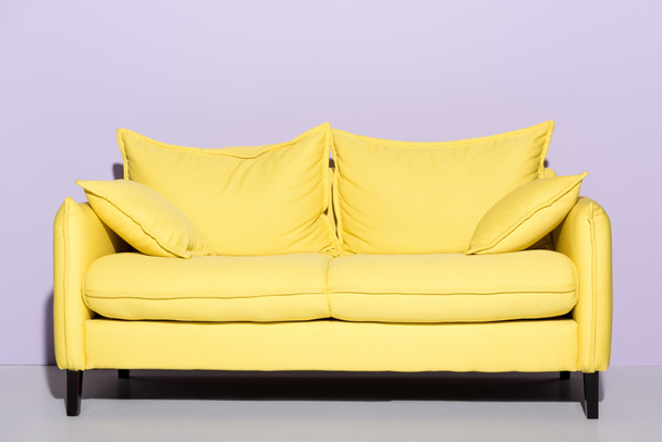 comfy yellow couch in front of pink wall - Fotografie, Obrázek
