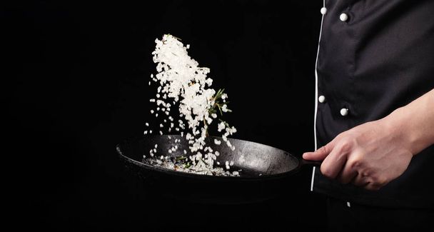 Főzés egy serpenyőben sült aromás só chef kézzel. Vízszintes fénykép megtekintése. Sötét, fekete háttér, a másolási szöveg terület - Fotó, kép