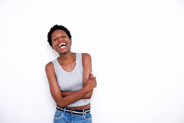 Πορτρέτο του γέλιου νεαρός αφρικανική αμερικανική γυναίκα με τα χέρια σταυρωμένα σε λευκό φόντο - Φωτογραφία, εικόνα