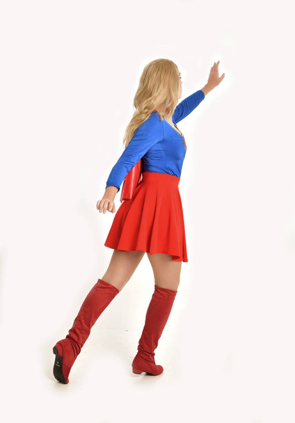 портрет красивой девушки в костюме супергероя, стоящей позе, изолированной на белом фоне студии
. - Фото, изображение