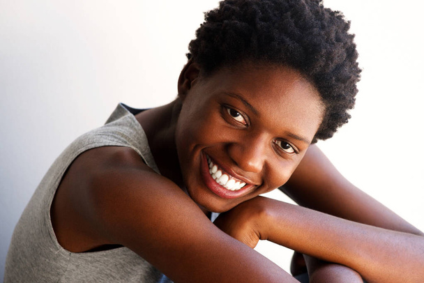 Detailní záběr portrét krásné mladé africké ženy sedí a usmívá se - Fotografie, Obrázek