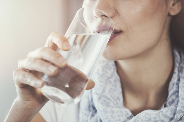 Молодая женщина пьет чистый стакан воды
 - Фото, изображение