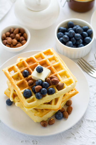 Healthy breakfast. Belgian waffles with butter, blueberry and nuts on white tablecloth. Selective focus - Foto, afbeelding