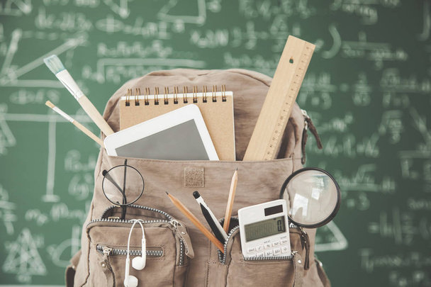 Backpack school with supplies in front of  green chalkboard - 写真・画像
