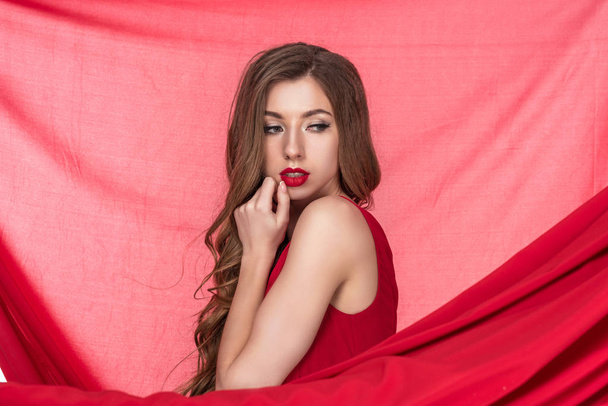 attractive sensual girl posing in red dress with red chiffon veil on background - Foto, Imagem