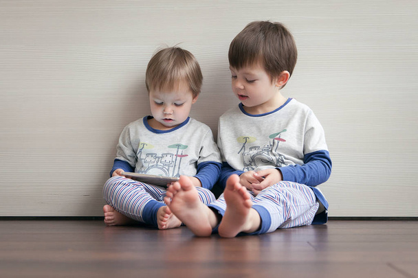 Dva bratři ve stejném pyžamo hrát hry v miniaplikaci.  - Fotografie, Obrázek