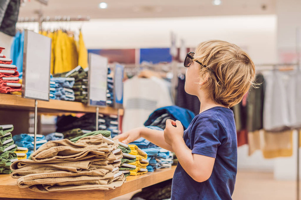Little boy trying on clothes in child clothing store - 写真・画像