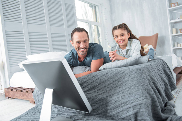 Positive joyful father and daughter lying on the bed - Photo, image