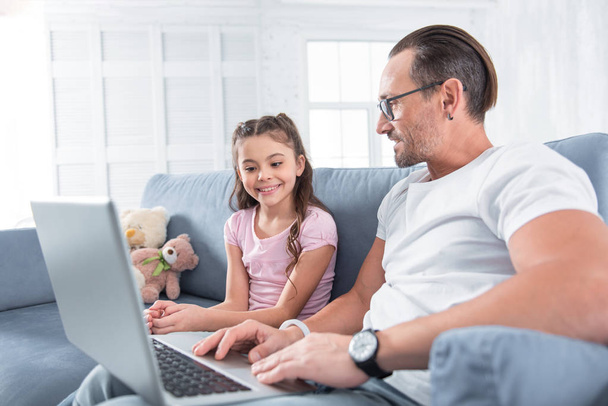 Happy smart man showing a laptop to his daughter - Photo, image