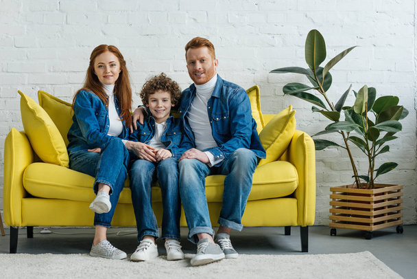 Smiling parents and son sitting on sofa in room - Fotografie, Obrázek