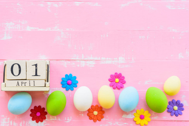 Wooden block calendar for Easter Day, April 1. Row Easter eggs with colorful paper flowers and red ribbon on bright pink and white wooden background. - Photo, Image