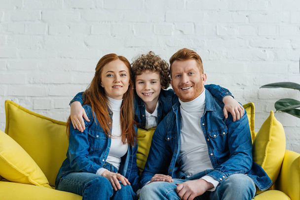 Hugging son and parents sitting on sofa - Foto, afbeelding