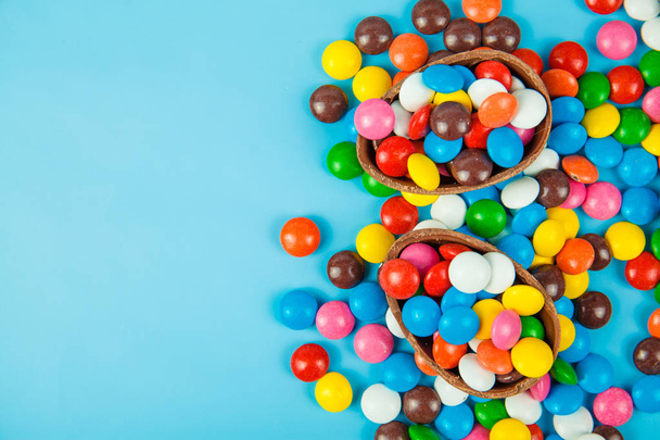 Шоколадные яйца и глазури цвета конфет на голубом фоне
 - Фото, изображение