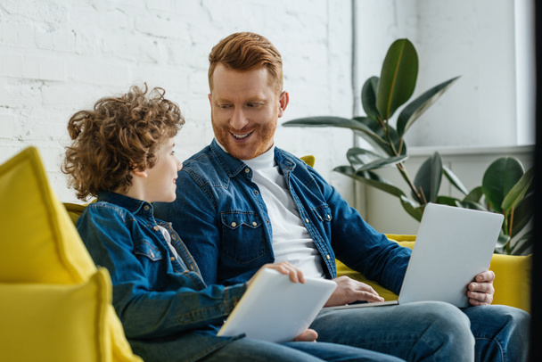 Smiling father with son using tablet and laptop - Photo, Image