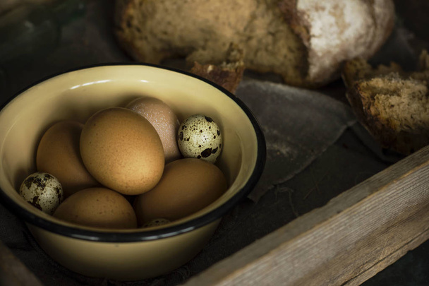 Os ovos de galinha e codorniz em tigela de metal com pão
  - Foto, Imagem