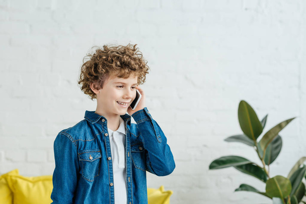 Маленький хлопчик з кучерявим волоссям розмовляє по телефону
 - Фото, зображення