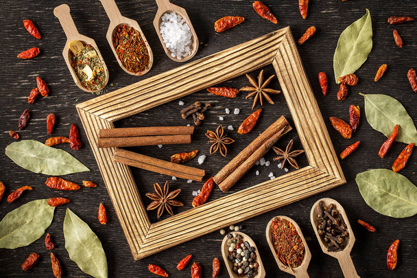 Various spices in wooden spoons  on dark stone table. - 写真・画像