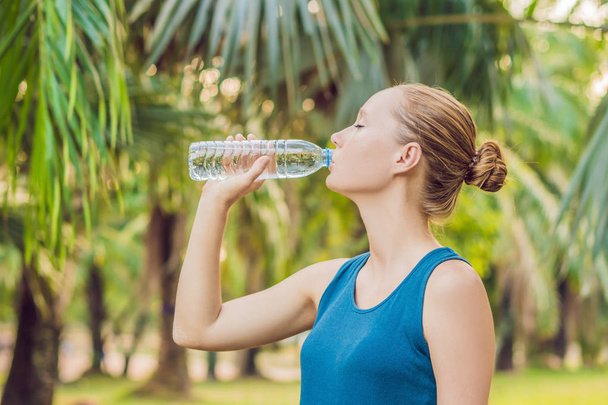 Attractive sporty woman drinking water from a bottle after jogging or running. - Фото, изображение