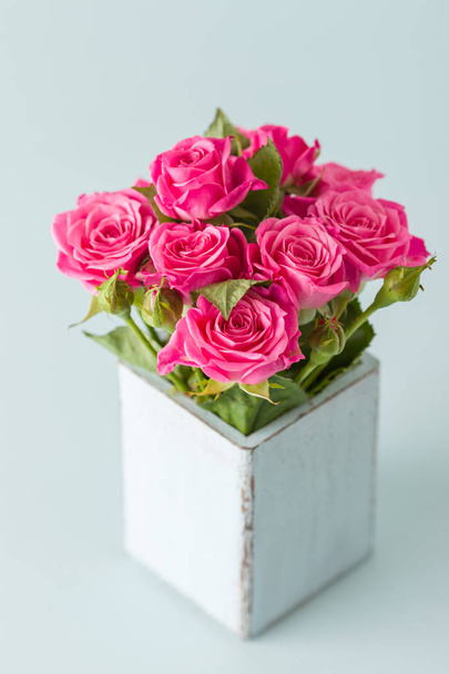 Прекрасний букет зі свіжих рожевих троянд у ретро-шорсткій шикарній вазі на пастельно-блакитному фоні
. - Фото, зображення