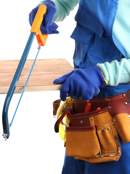 Male builder in blue overalls sawing board isolated on white - 写真・画像