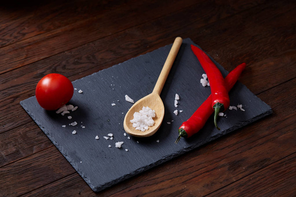 Vegetarian still life with fresh grape tomatoes, pepper and salt in wooden spoon on wooden background, selective focus - 写真・画像