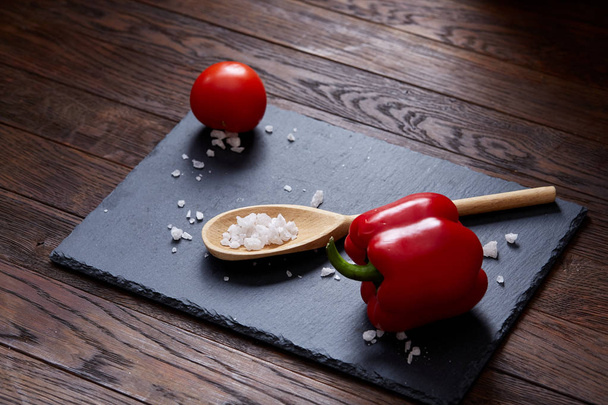 Vegetarian still life with fresh grape tomatoes, pepper and salt in wooden spoon on wooden background, selective focus - 写真・画像