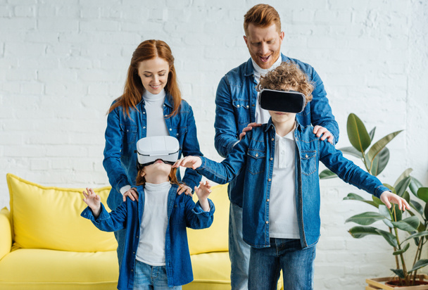 Crianças usando óculos VR em pé na frente de seus pais sorridentes
 - Foto, Imagem