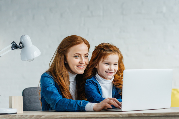 Woman and child looking at laptop screen - Fotó, kép