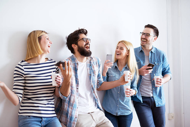 ryhmä nuoria onnellisia työtovereita pitää hauskaa tauolla juodessaan kahvia
 - Valokuva, kuva
