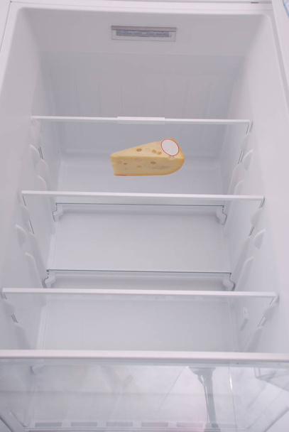 Ένα τυρί στο ανοιχτό άδειο ψυγείο. - Φωτογραφία, εικόνα