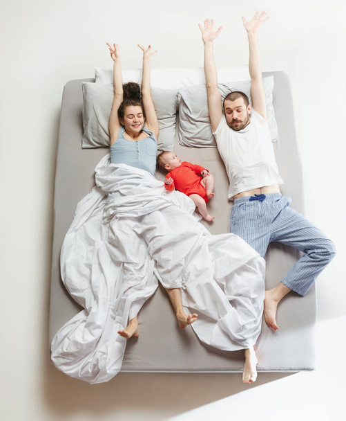 Top view of happy family with one newborn child in bedroom. - Foto, Bild