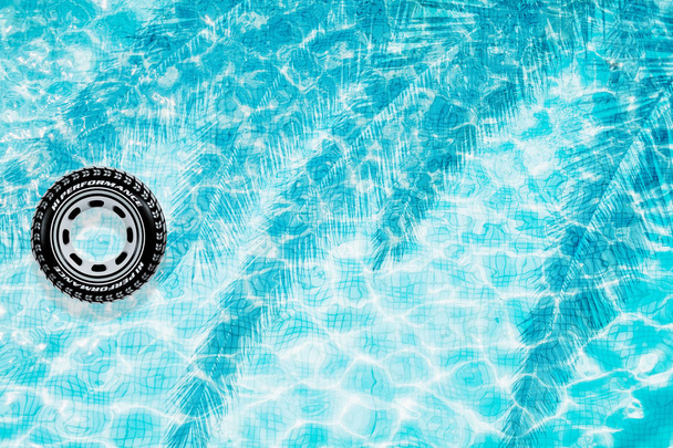 Vista superior do fundo da piscina com pneu de carro inflável e sombra de palma
 - Foto, Imagem