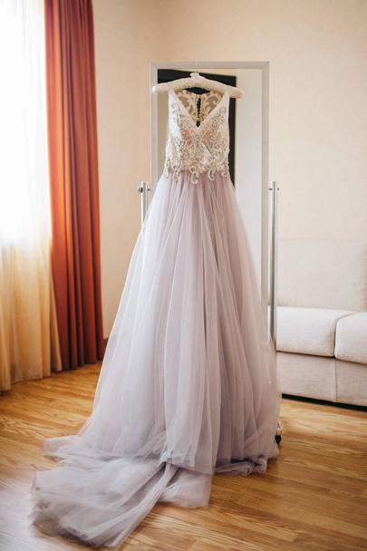 Purple wedding dress hanging on a mirror in the room - Fotoğraf, Görsel