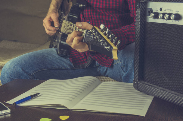 hipster musician sits on the couch and plays the electric guitar - Foto, Imagen