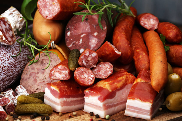 Futtertablett mit leckeren Salami, Schinken, frischen Würsten, Gurken und Kräutern. Fleischplatte mit Auswahl - Foto, Bild
