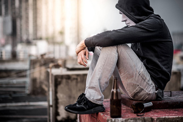 Таинственный человек в маске сидит с пустыми и разбитыми бутылками
 - Фото, изображение