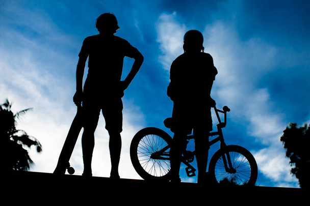 Οπίσθια όψη των δύο νεαρός άνδρας BMX ποδήλατο και skateboard - Φωτογραφία, εικόνα